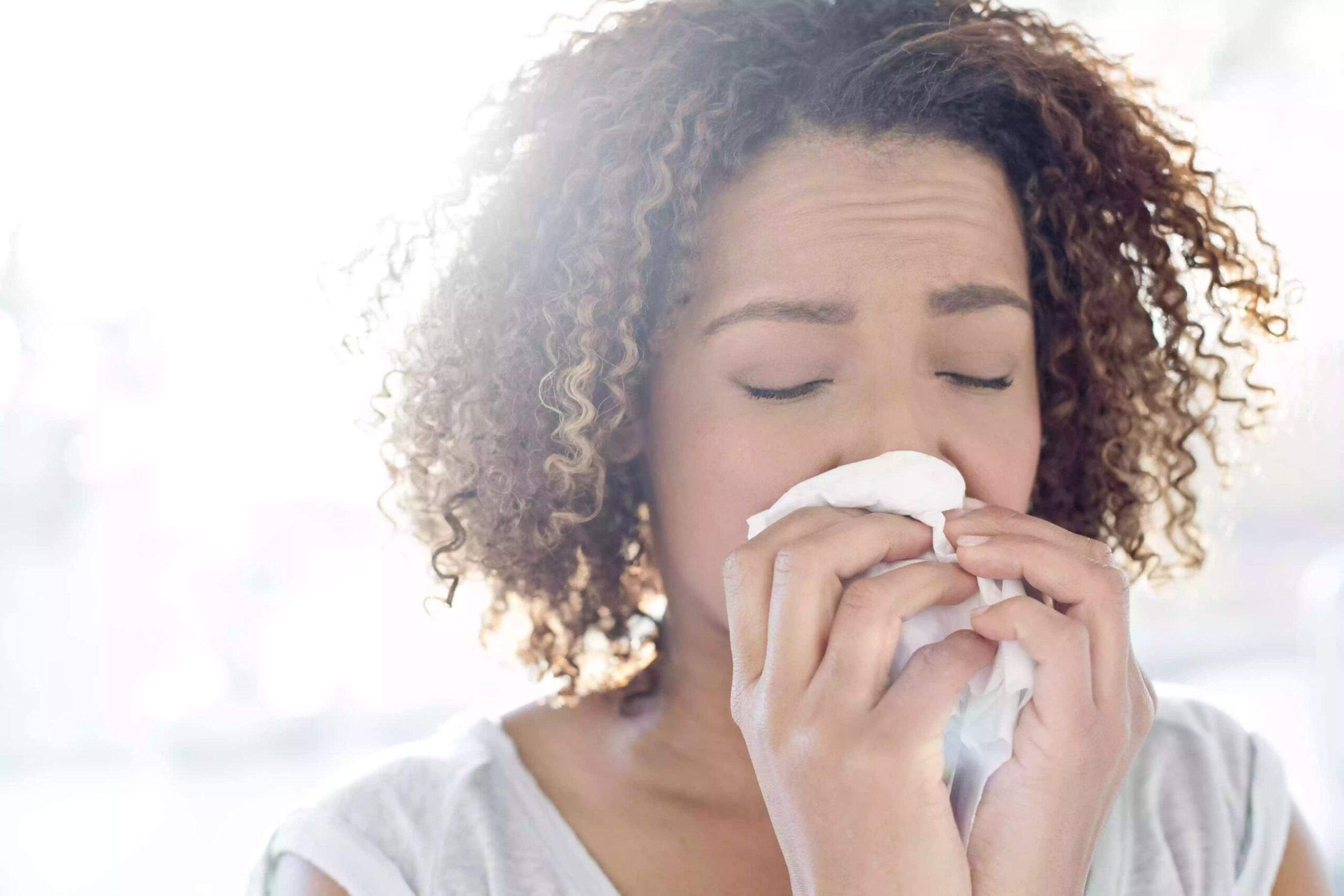 Woman blowing nose on tissue